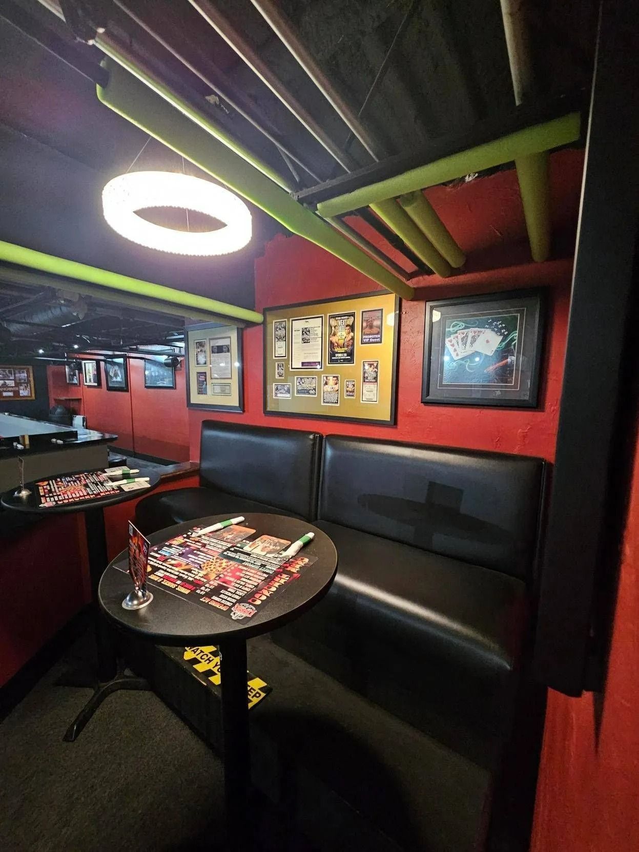 Cozy red-and-black booth seating in a dimly lit restaurant with a round table and wall art