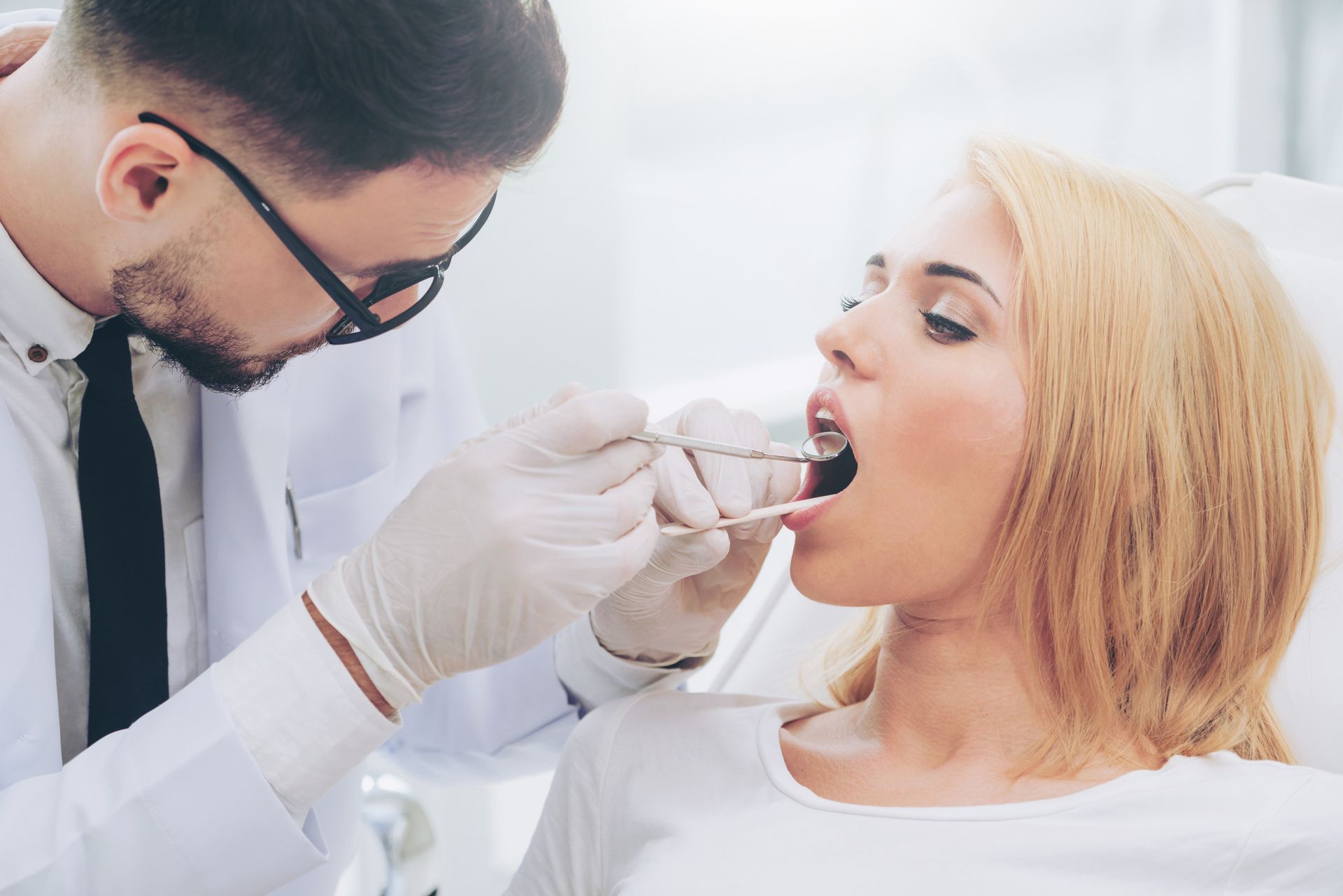 Dentist performing oral examination on patient in modern dental clinic.