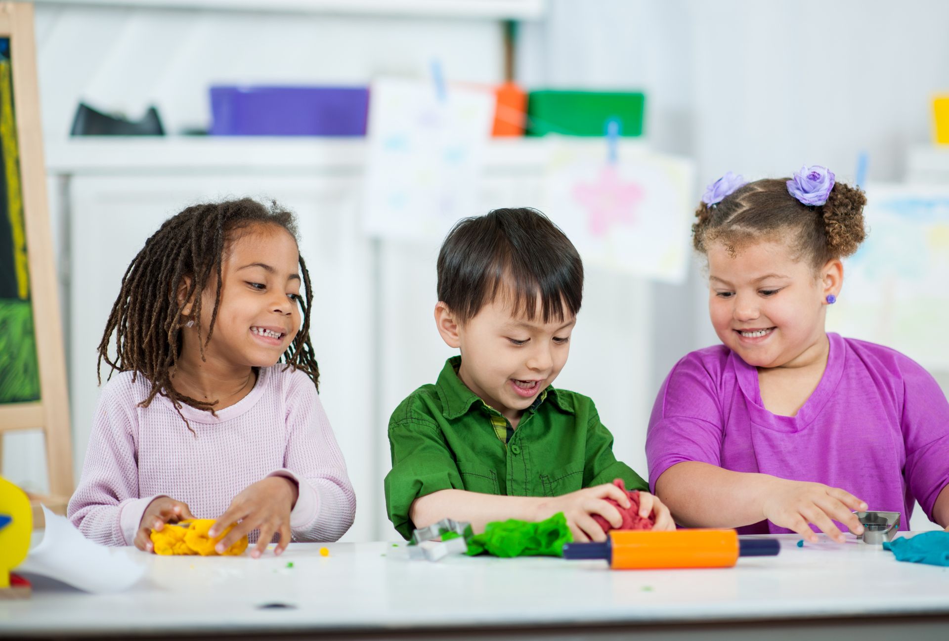 Children shaping colourful clay at a classroom activity table.