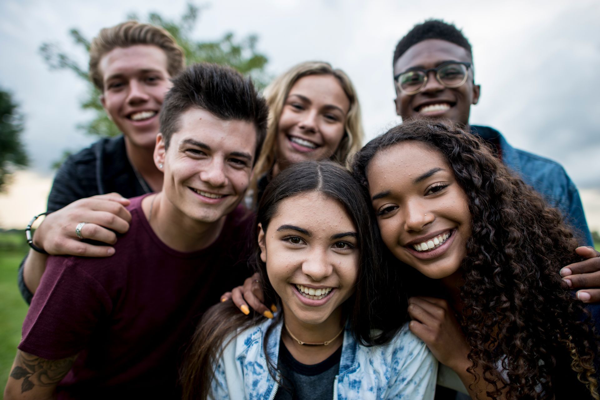 A group of young people are posing for a picture in a park.