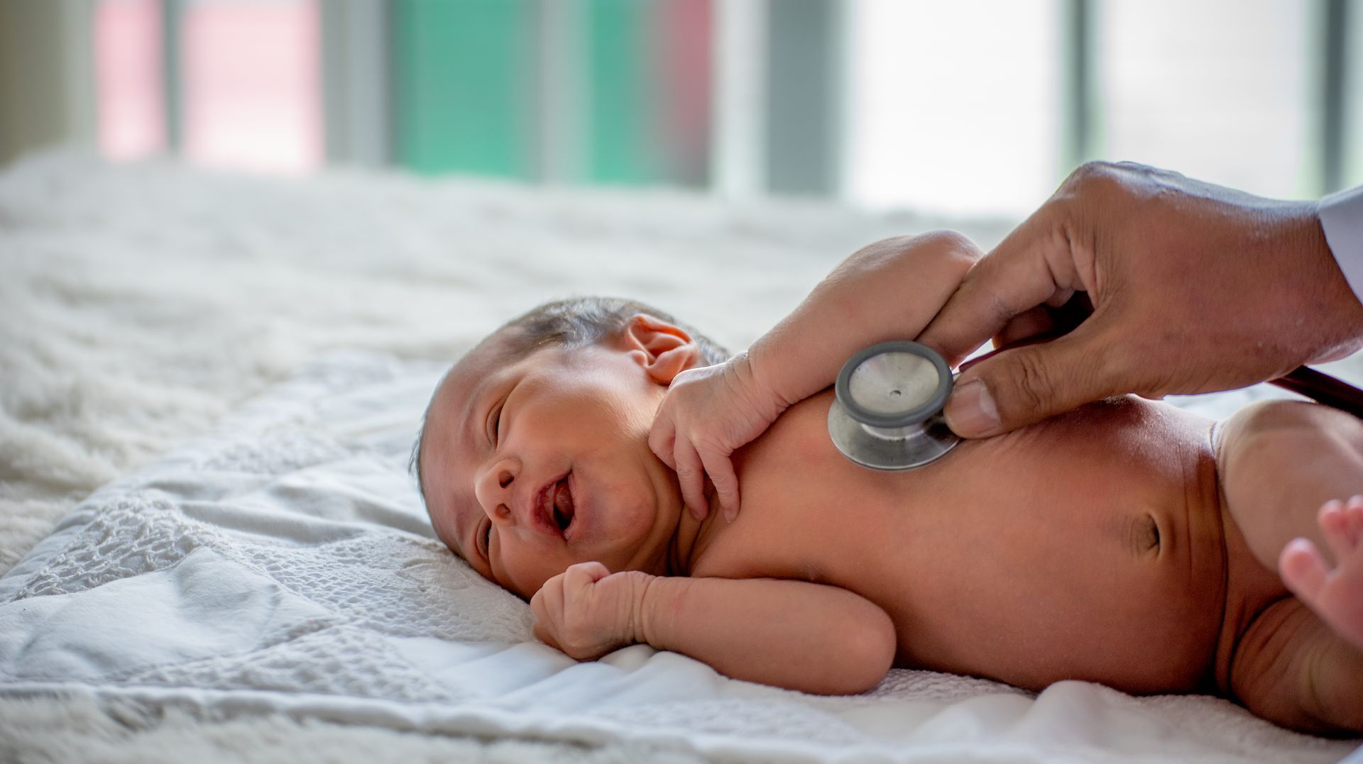 A baby is being examined by a doctor with a stethoscope.