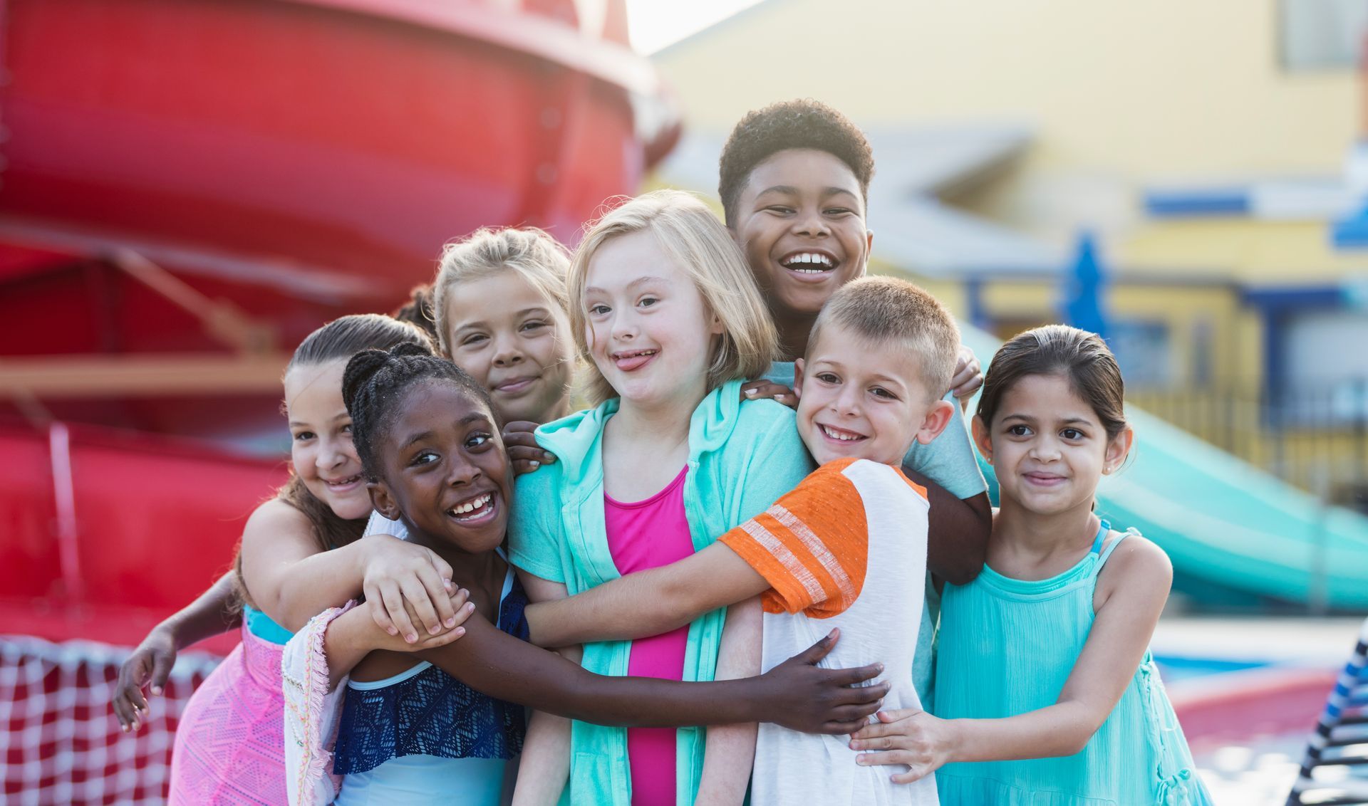 A group of children are hugging each other at a water park.