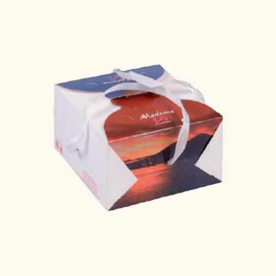 Scatola regalo con ornamento rosso e nastro bianco su sfondo chiaro.