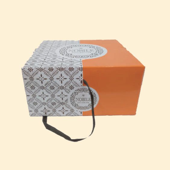 Scatola regalo arancione e decorata con manico in nastro su sfondo beige.
