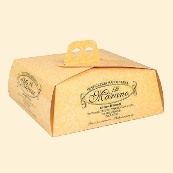 Scatola per dolci in cartone giallo con manico ed etichetta stampata su sfondo chiaro.