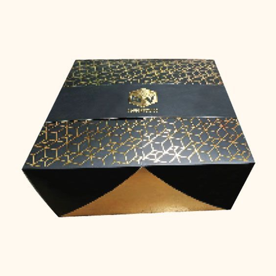 Scatola regalo con motivo nero e oro e logo dorato sul coperchio, con apertura frontale che rivela un interno nero e oro.