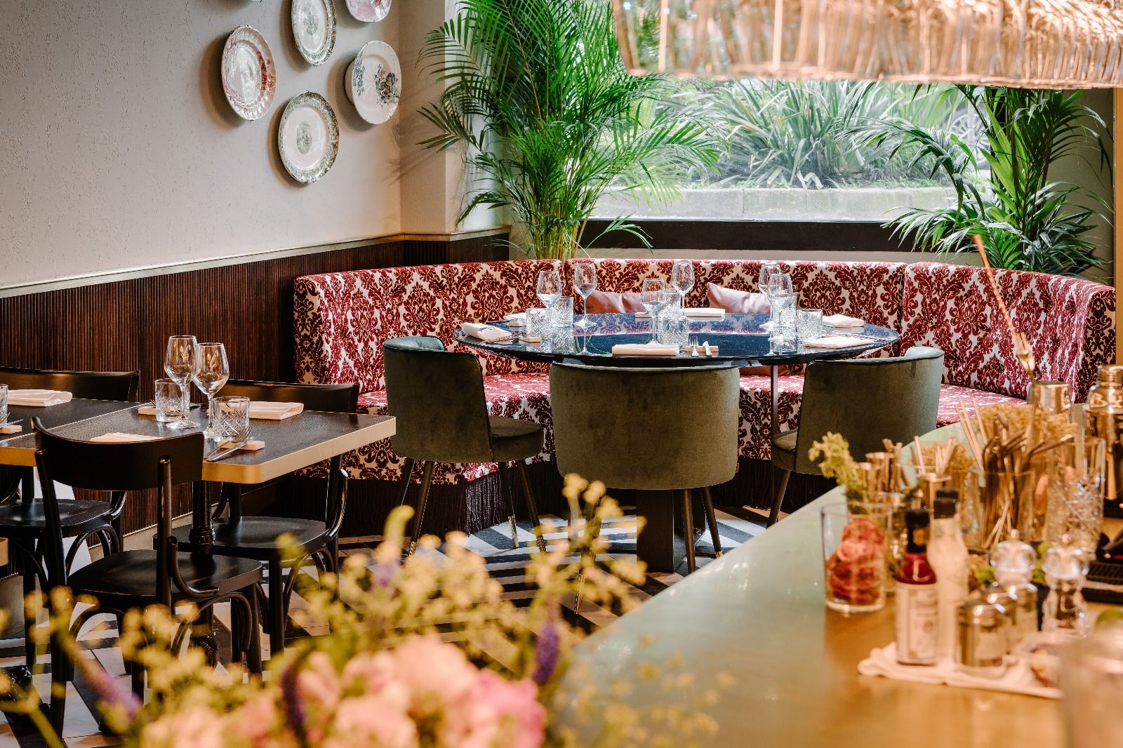 Elegante comedor de restaurante con mesas puestas, cómodos reservados, platos en la pared y una luminosa vista