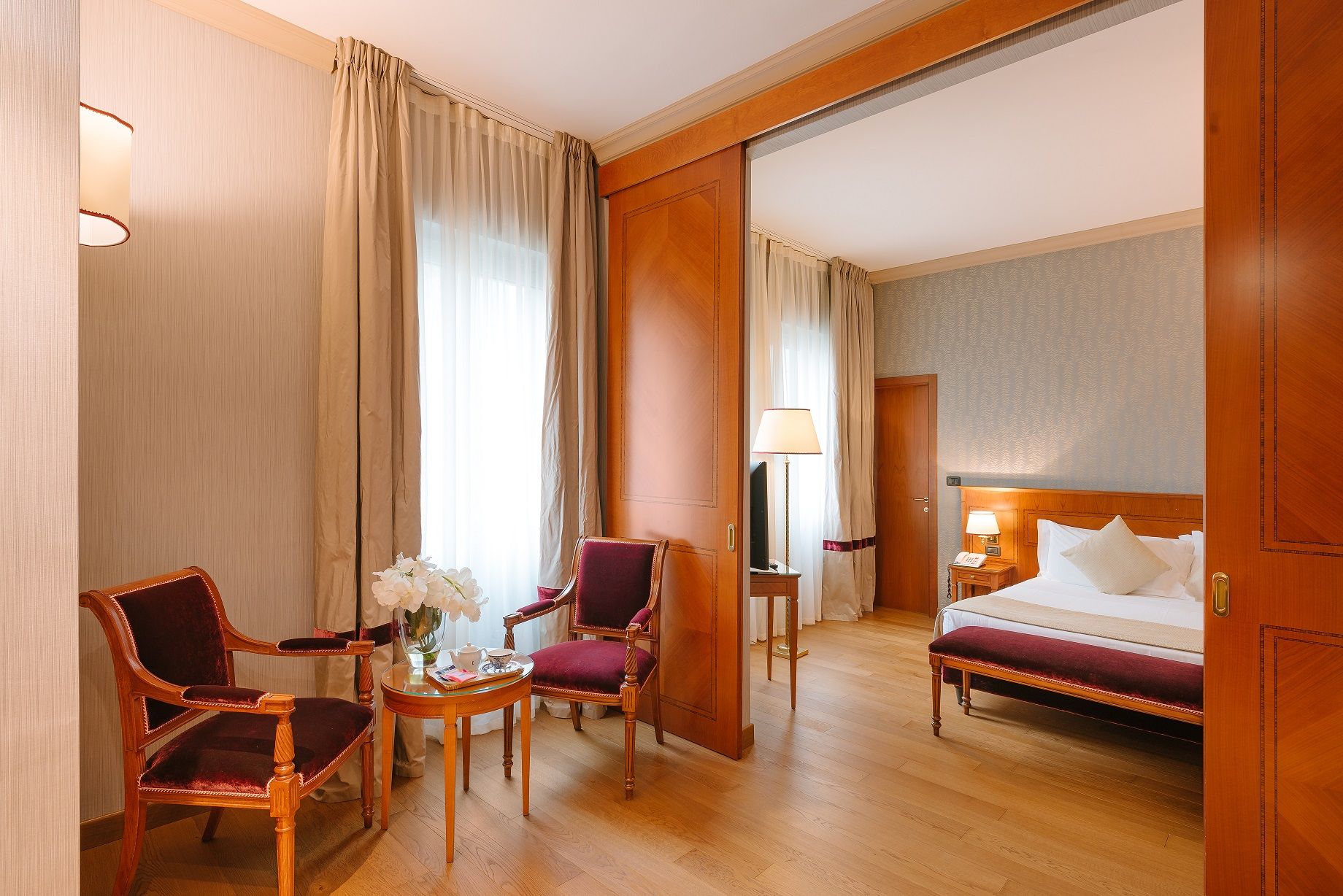 Acogedora habitación de hotel con cama, sillones, lámpara y separador corredizo con paneles de madera.