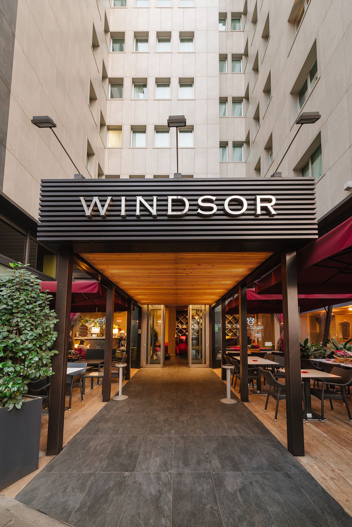 Entrada al hotel Windsor con toldo a rayas entre altos edificios de color beige.