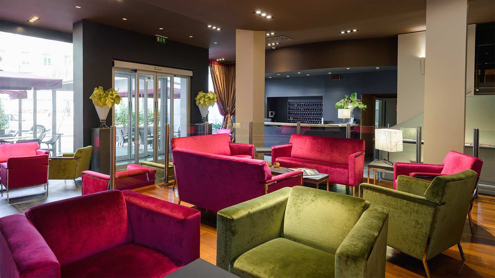 Salón moderno con coloridos sofás y sillones alrededor de una chimenea, iluminado por grandes ventanales