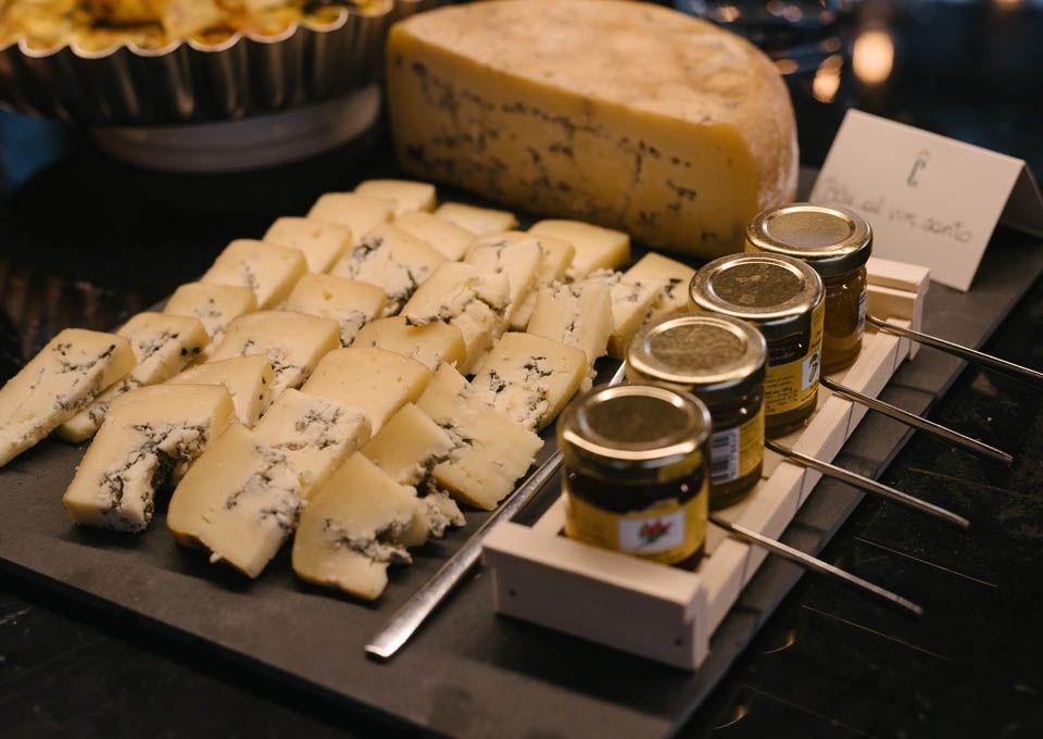 Assortimento di formaggi e barattoli di condimenti sul banco di un mercato o di una gastronomia.