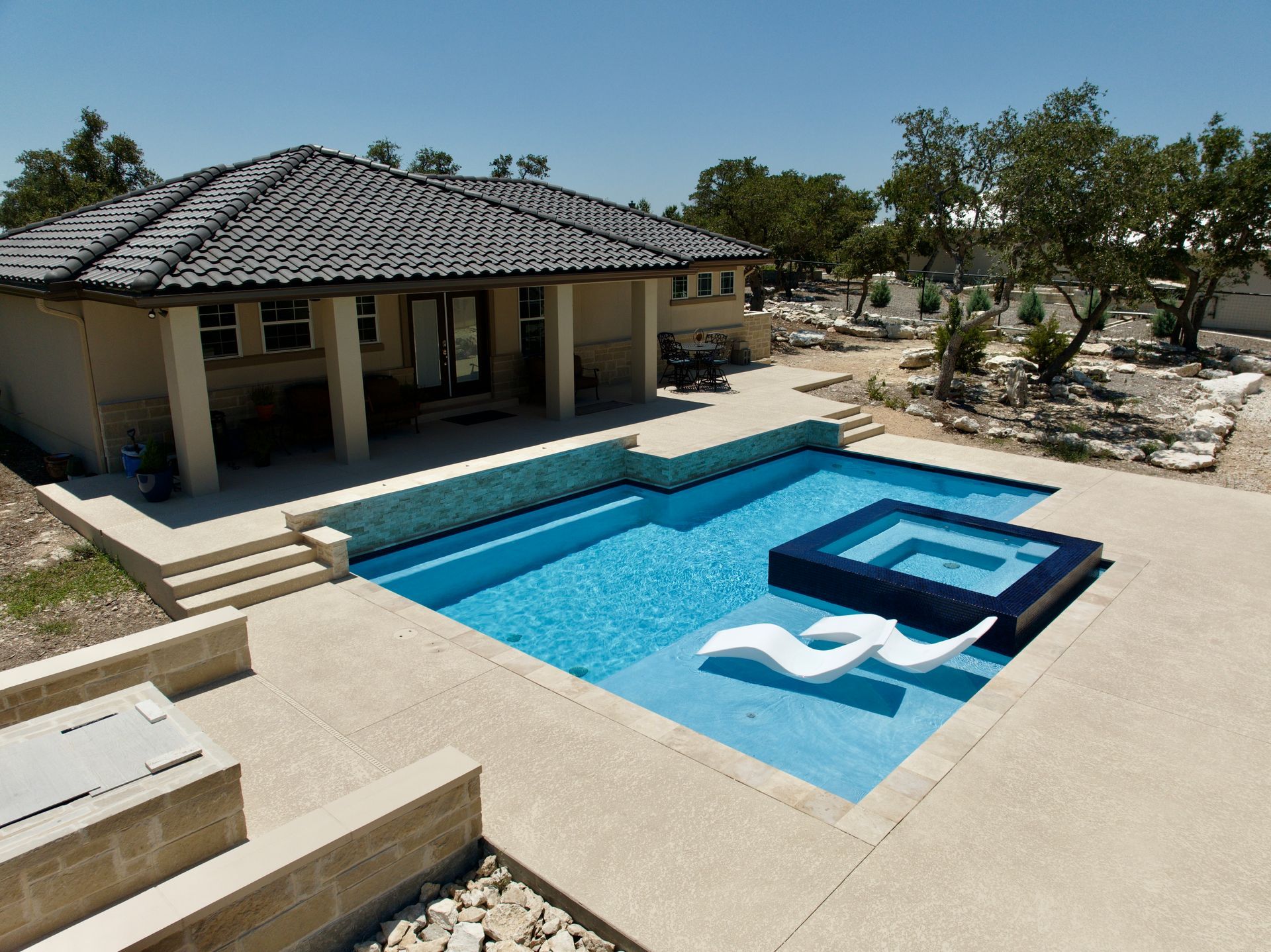 A house with a large swimming pool in front of it designed by Fine Patio Design San Antonio TX