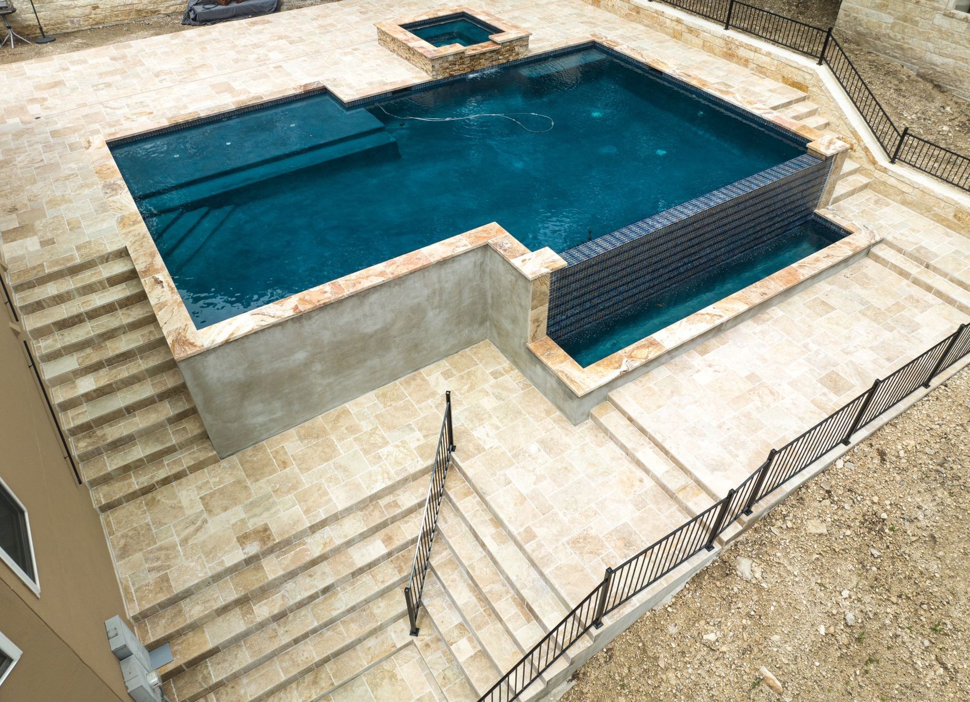 A large swimming pool with stairs leading up to it designed by Fine Patio Design San Antonio TX