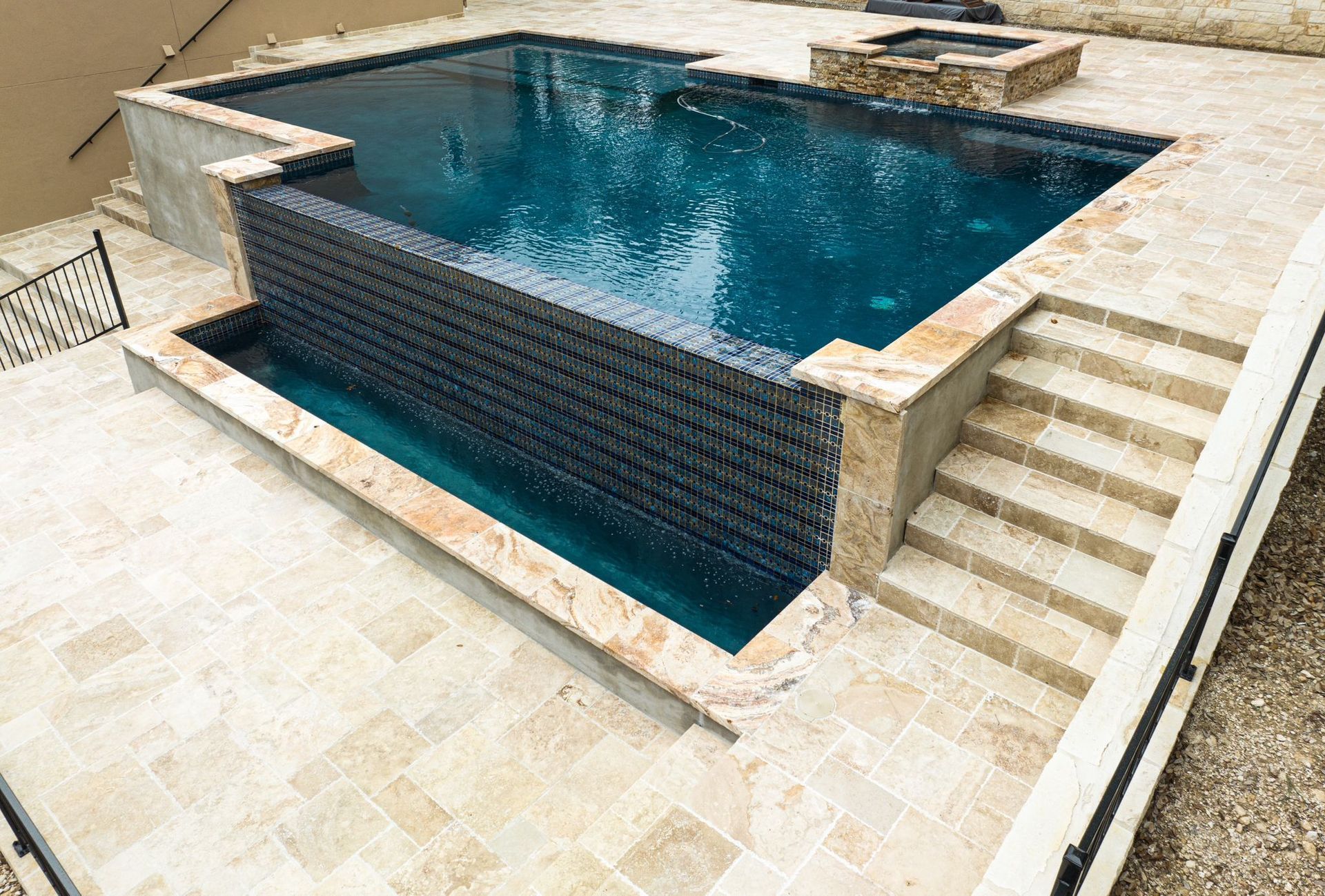 A large swimming pool with stairs leading up to it designed by Fine Patio Design San Antonio TX
