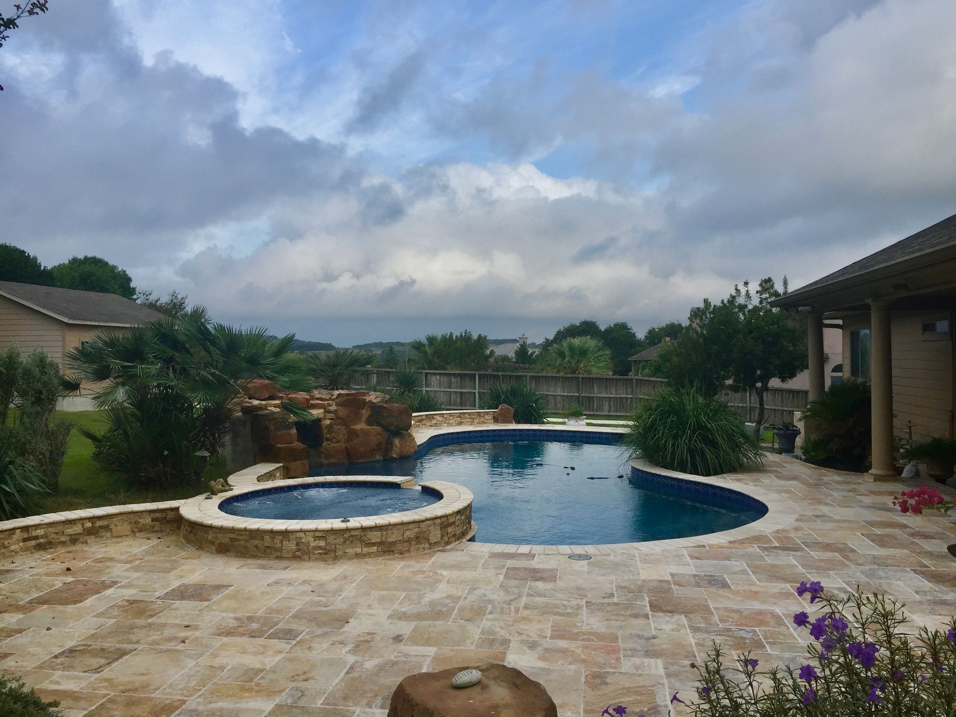 A large swimming pool with a hot tub in the backyard built by Fine Patio Design San Antonio TX