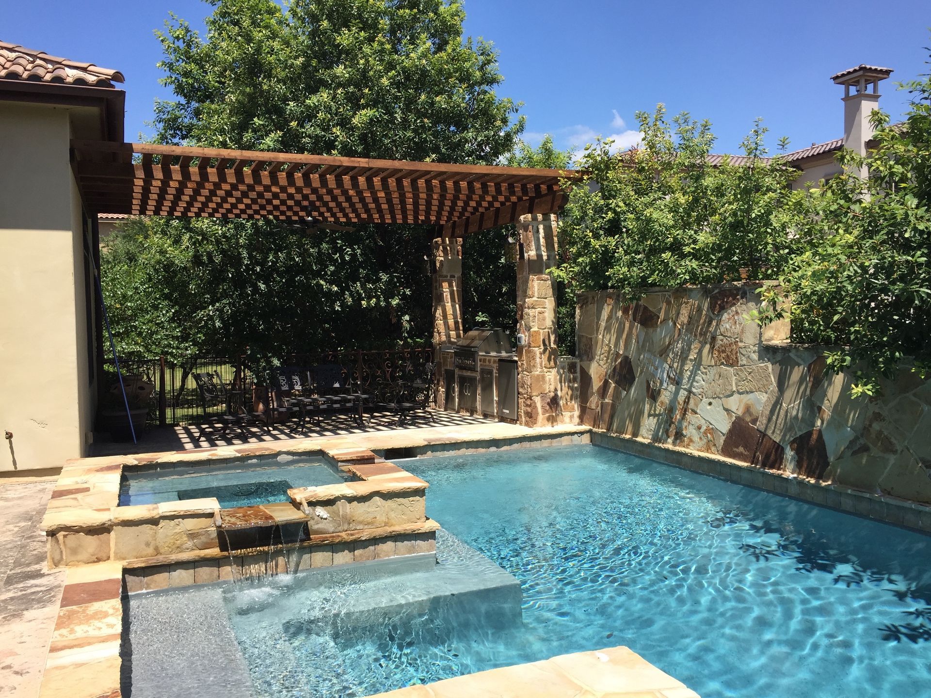 A large swimming pool with a pergola over it built by Fine Patio Design San Antonio TX