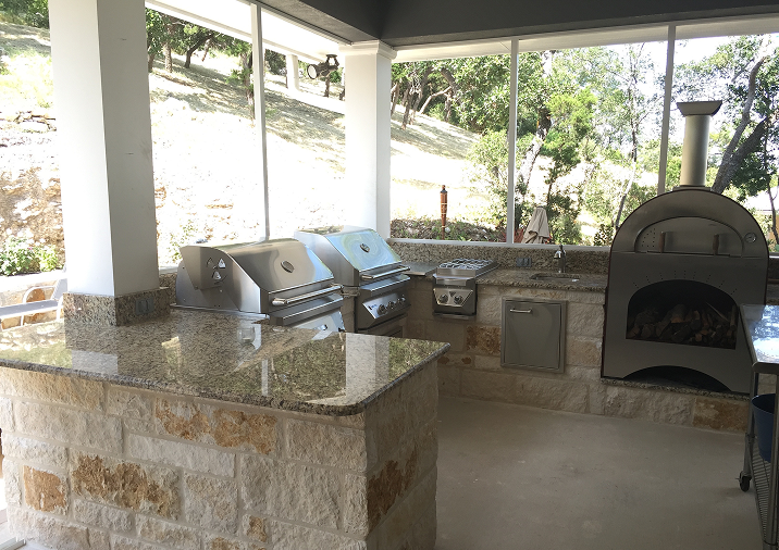 Outdoor kitchen with a pizza oven and ample counter space, featuring additional amenities