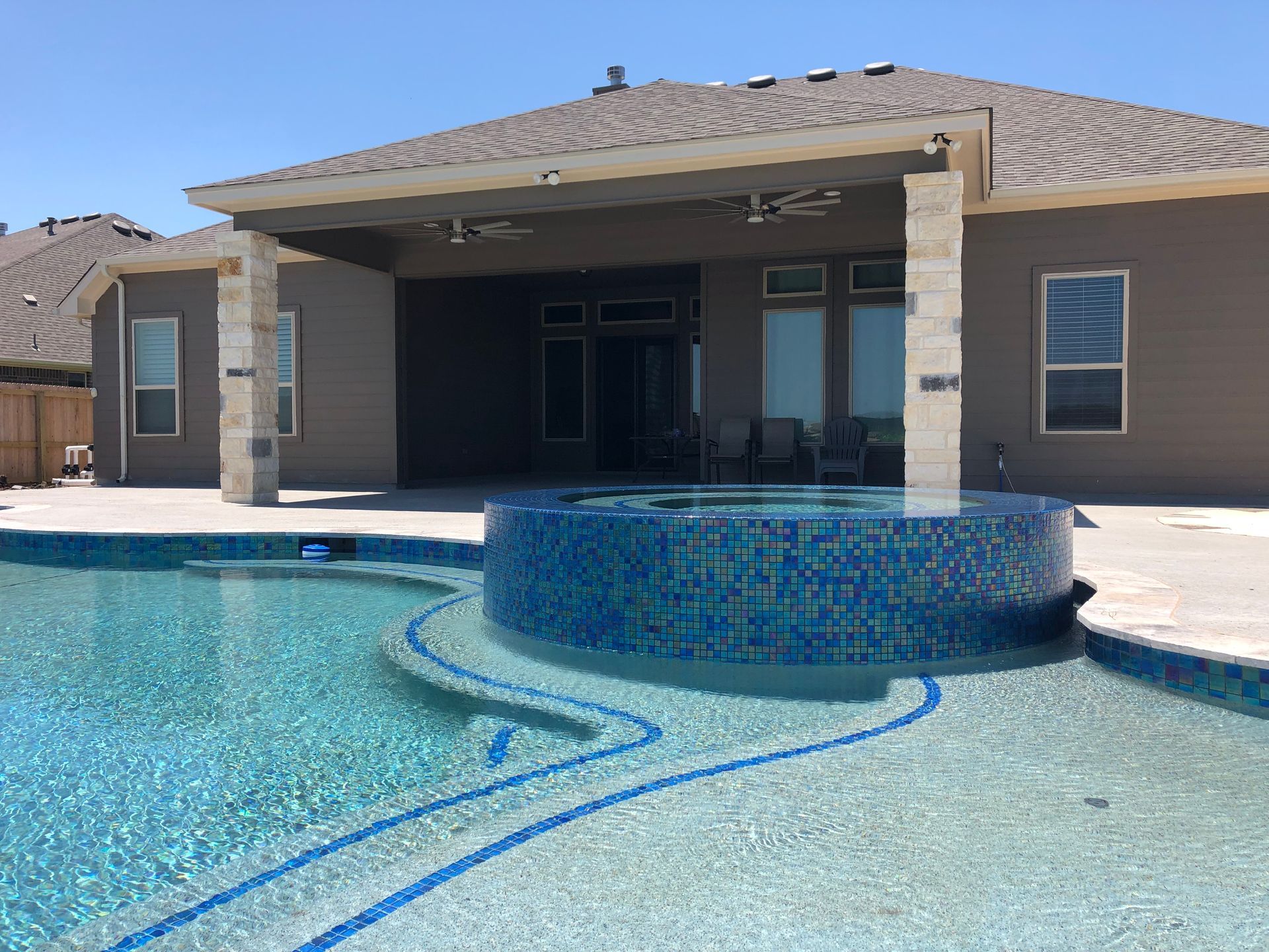 A house with a large swimming pool in front of it built by Fine Patio Design San Antonio TX