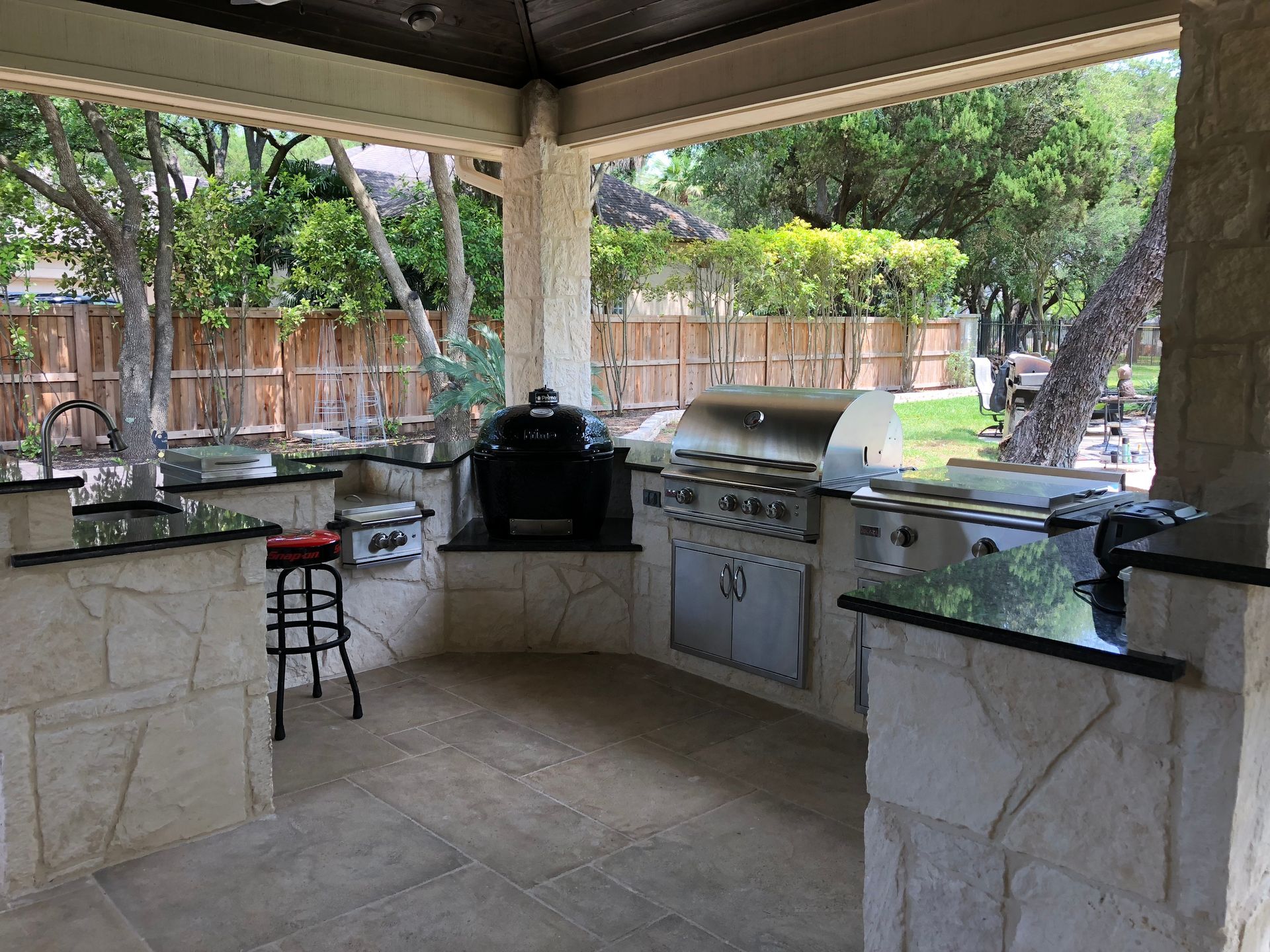 An outdoor kitchen with a stools and a grill built by Fine Patio Design San Antonio TX