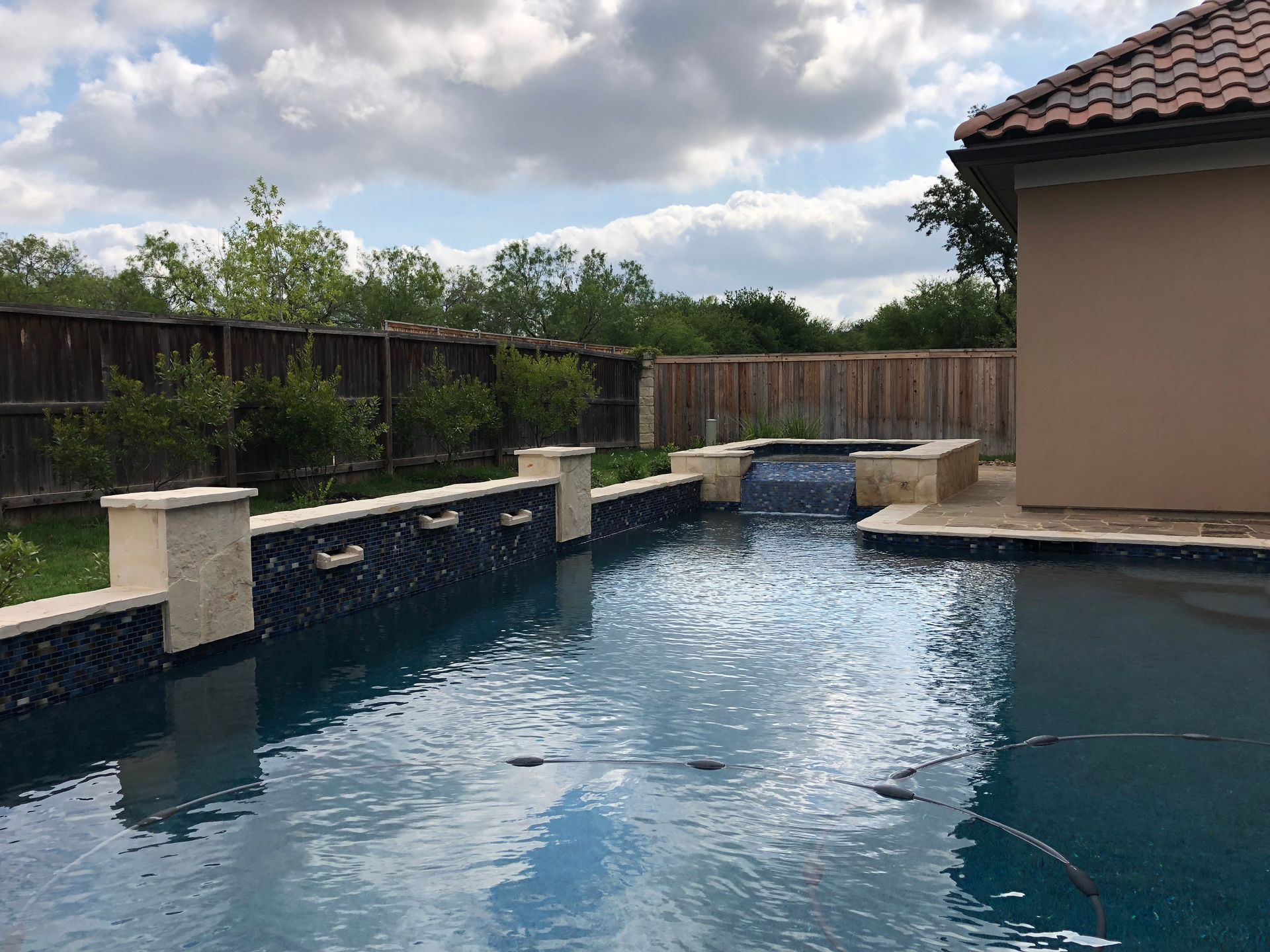 A large swimming pool with a waterfall in the backyard built by Fine Patio Design San Antonio TX