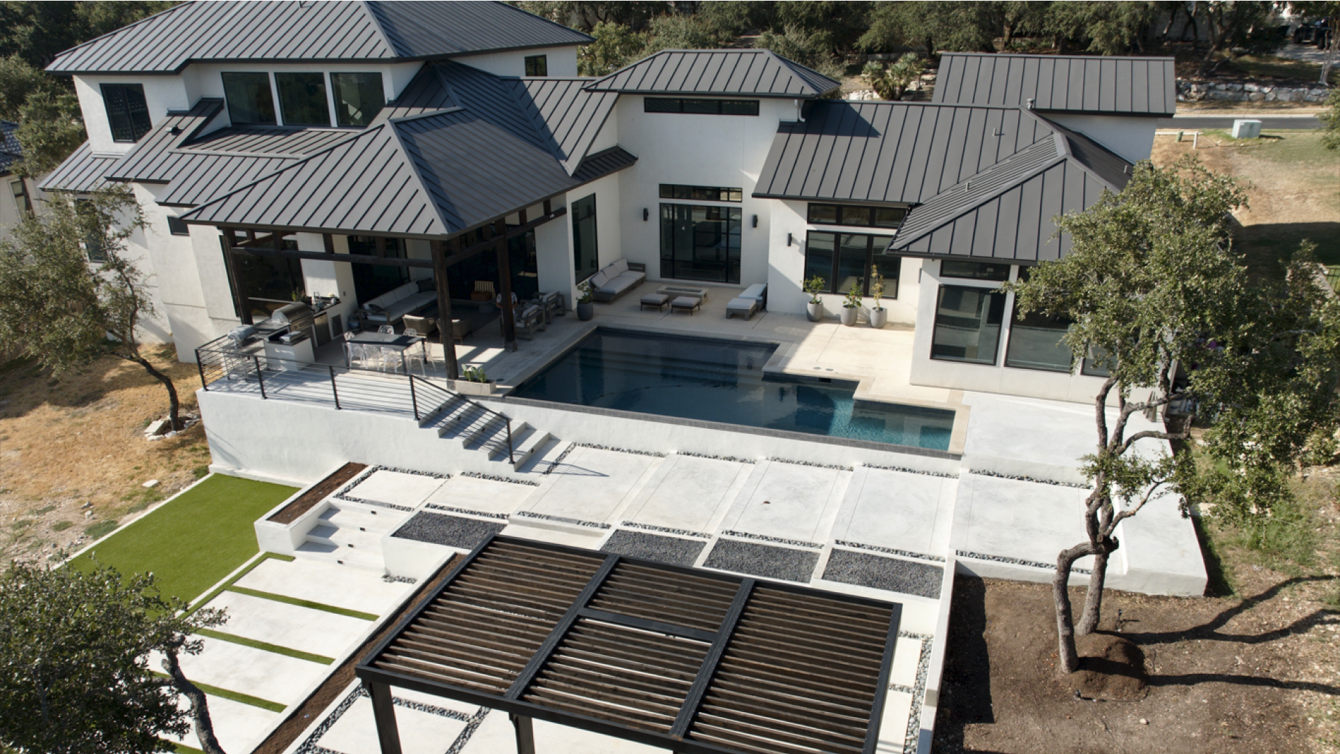 An aerial view of a house with a large swimming pool Designed by Fine Patio Design In San Antonio TX