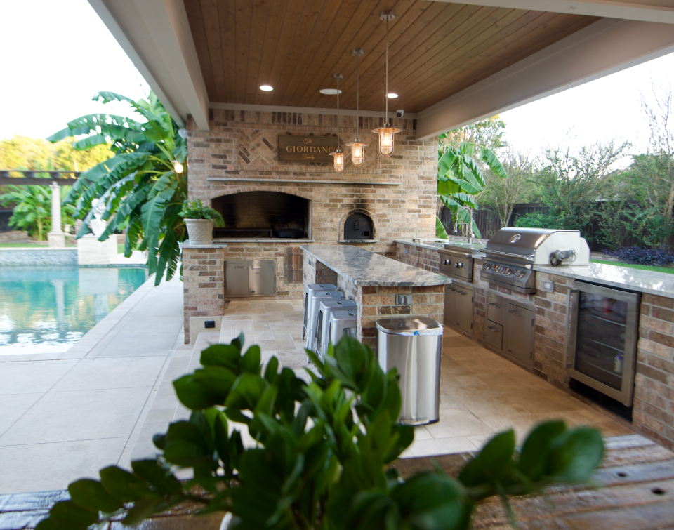 Custom-built outdoor kitchen with a stone fireplace and integrated appliances