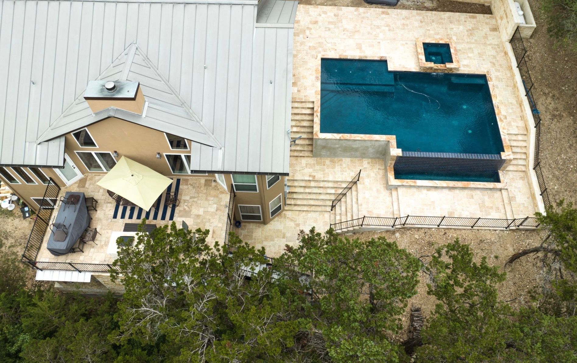 An aerial view of a house with a large swimming pool Designed by Fine Patio Design In San Antonio TX