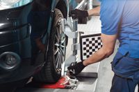 Mechanic using alignment equipment on a car tire in a repair shop | Fort Meade Auto Center
