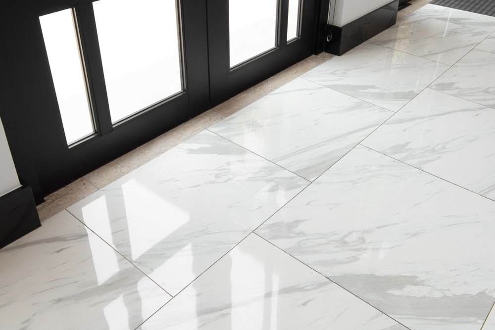 Marble-tile floor beside black-framed glass doors with bright light reflecting on the surface