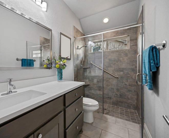 Modern bathroom with double vanity, glass-enclosed tiled shower, and toilet