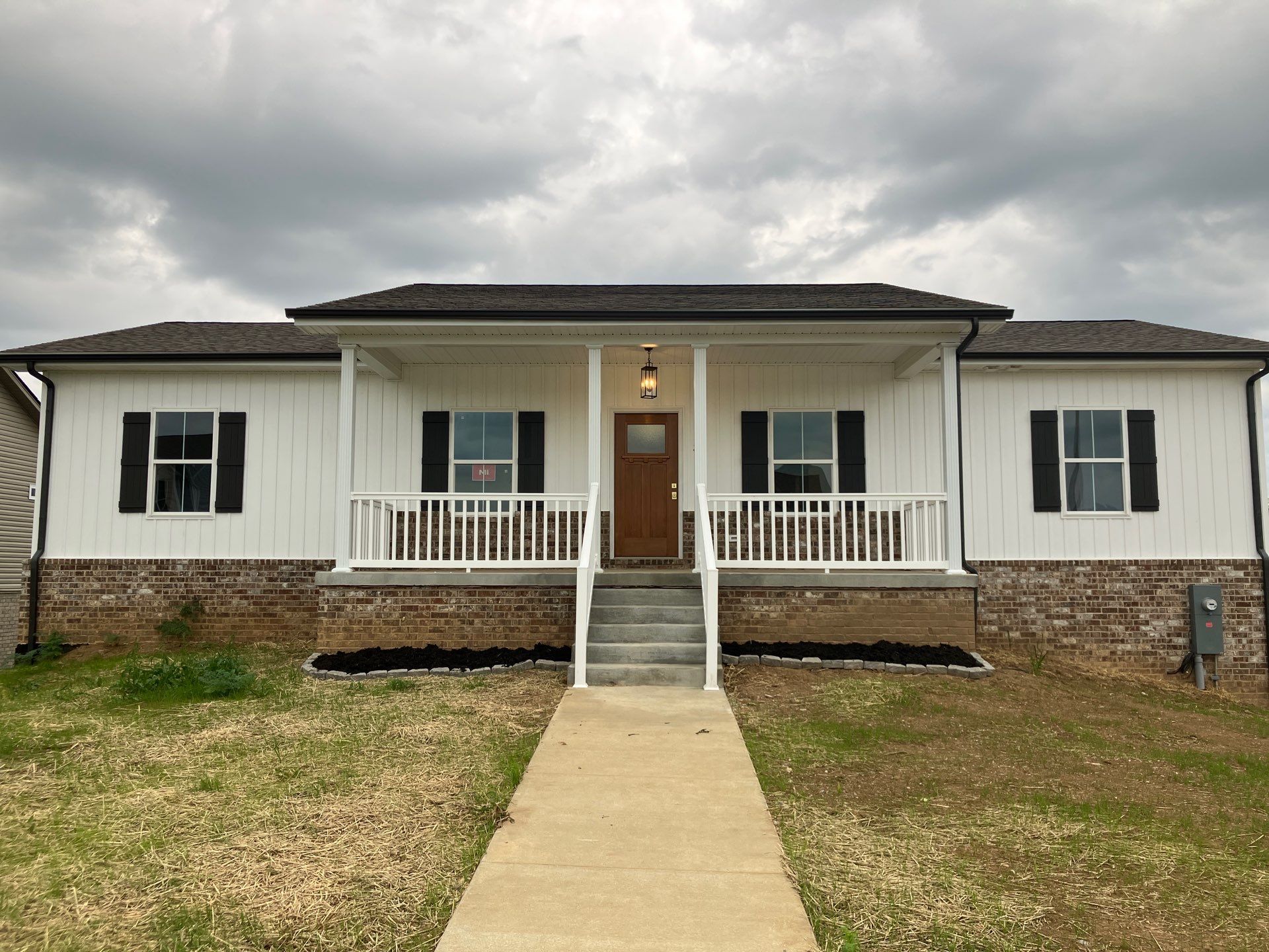 Single-story white house with front porch, stone foundation, and a walkway leading to the door