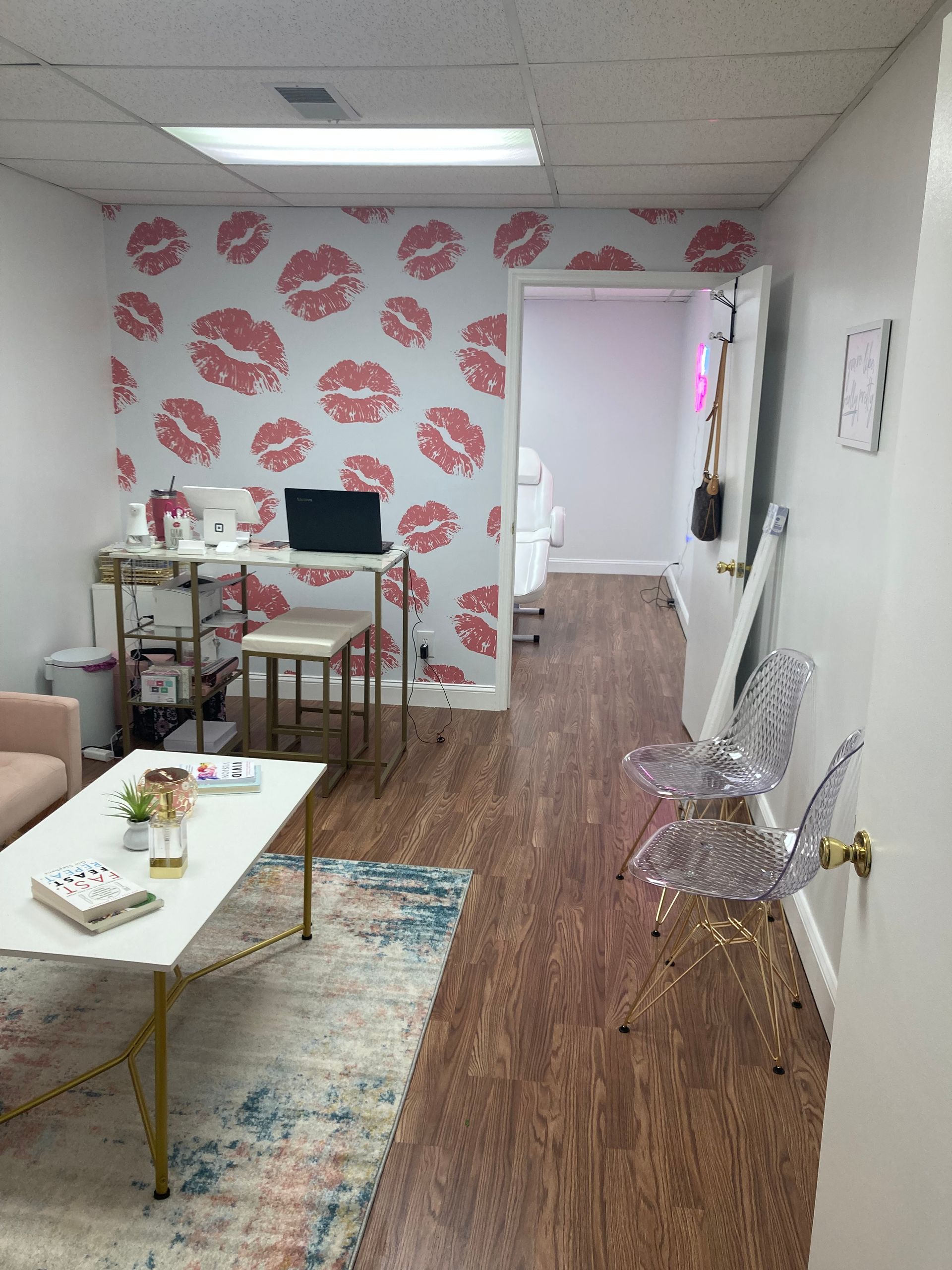 Small waiting room with lip-print wallpaper, tables, chairs, and a hallway leading to another room.