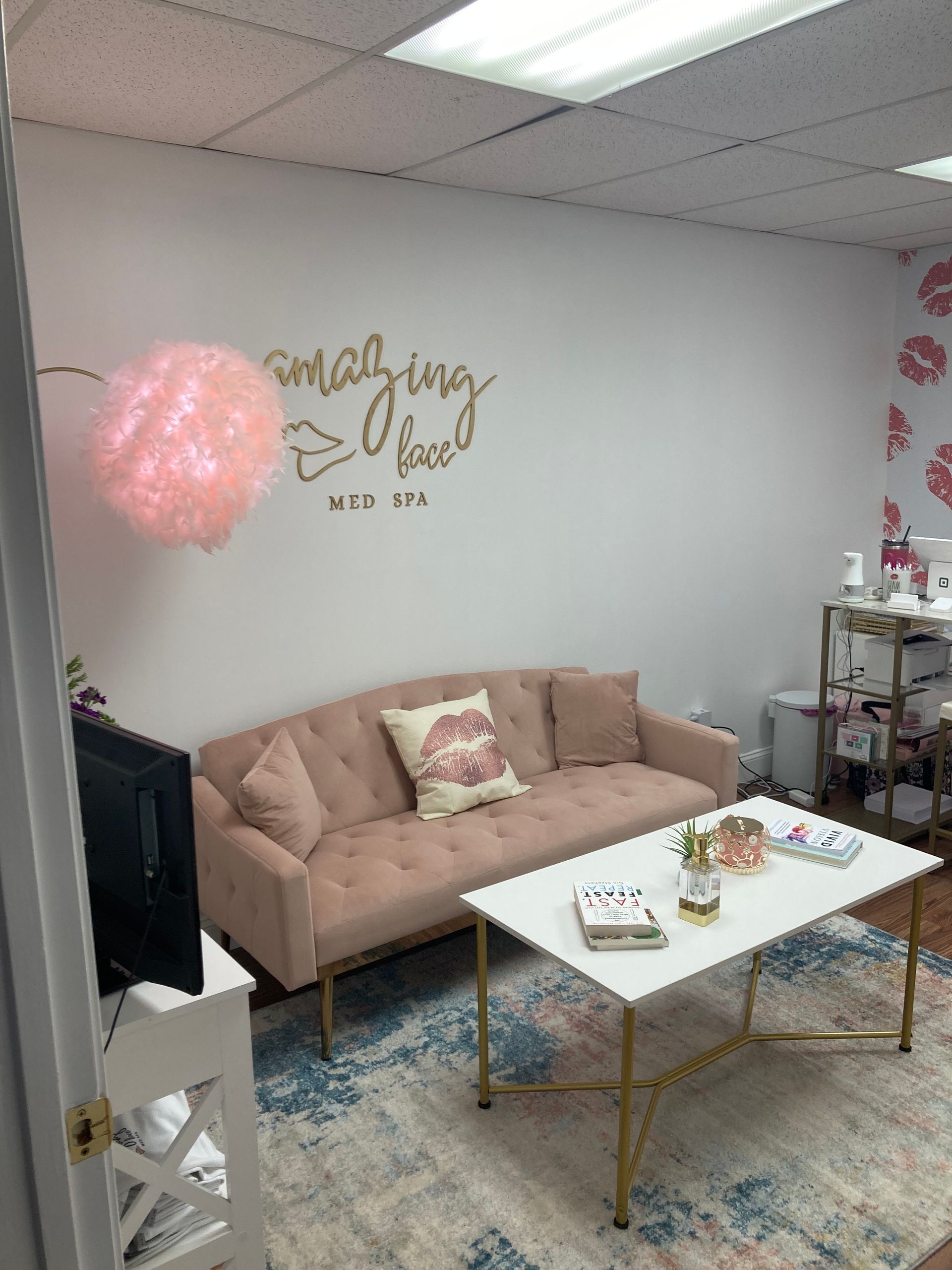 Pink-themed lounge with beige sofa, white coffee table, rug, and gold wall decor under a pink balloon lamp