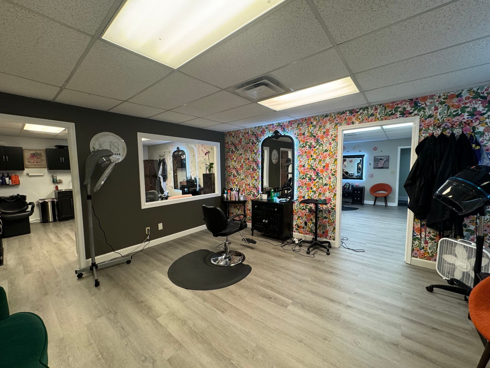 Hair salon interior with patterned walls, styling chairs, mirrors, and bright overhead lights