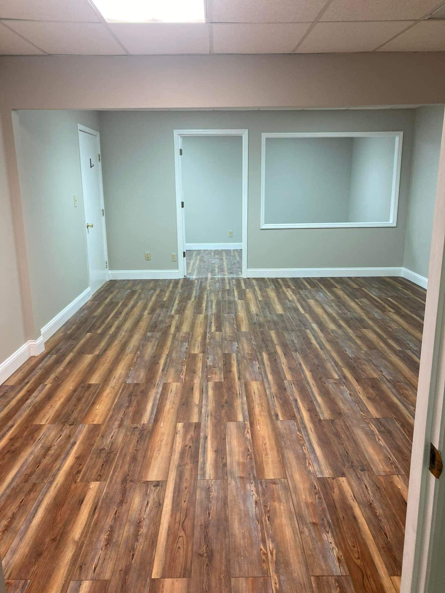 Empty room with wood-look flooring, gray walls, and white-trimmed doors and window opening.