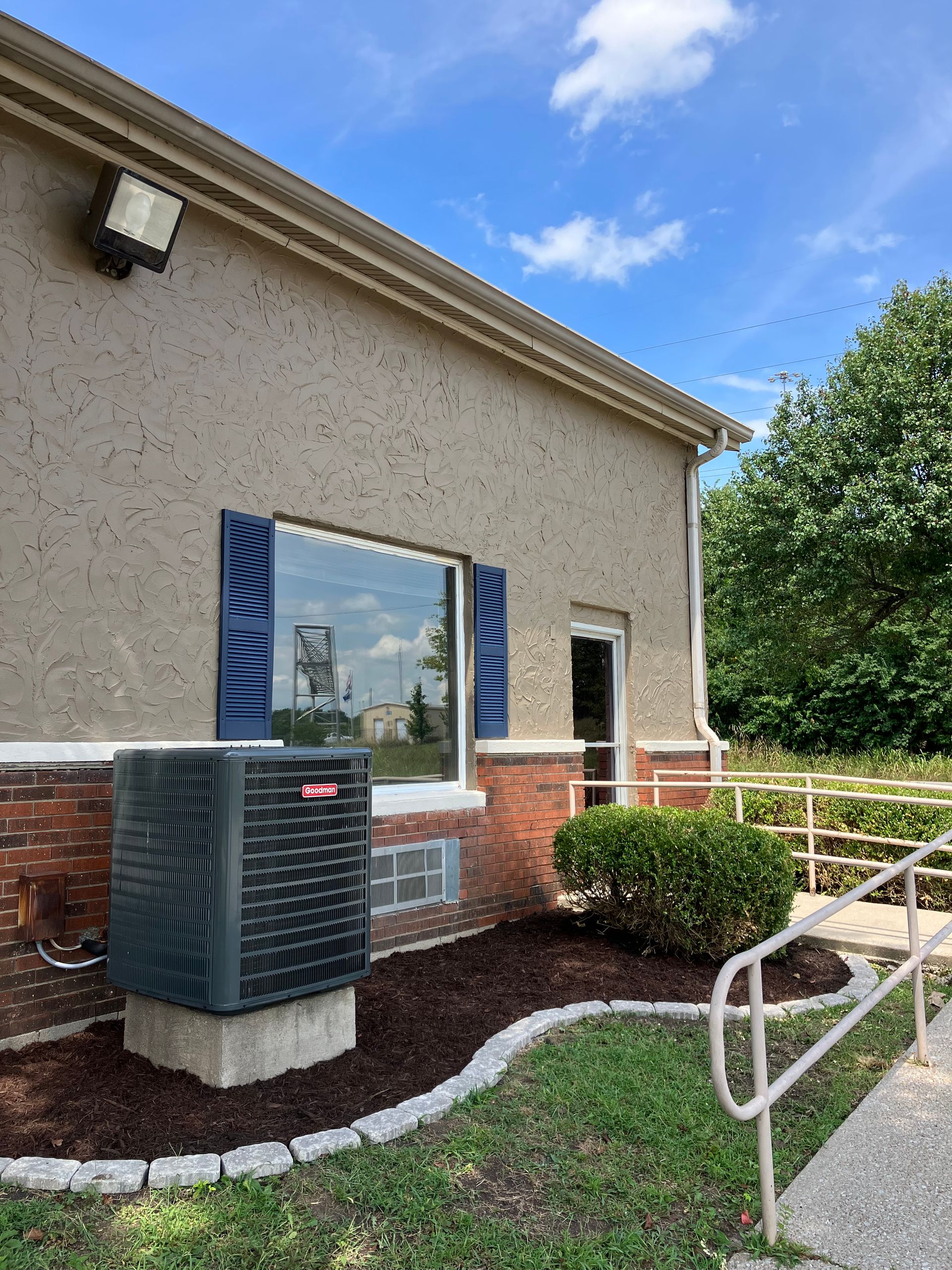 Building exterior with a window, HVAC unit, and wheelchair ramp beside a sidewalk