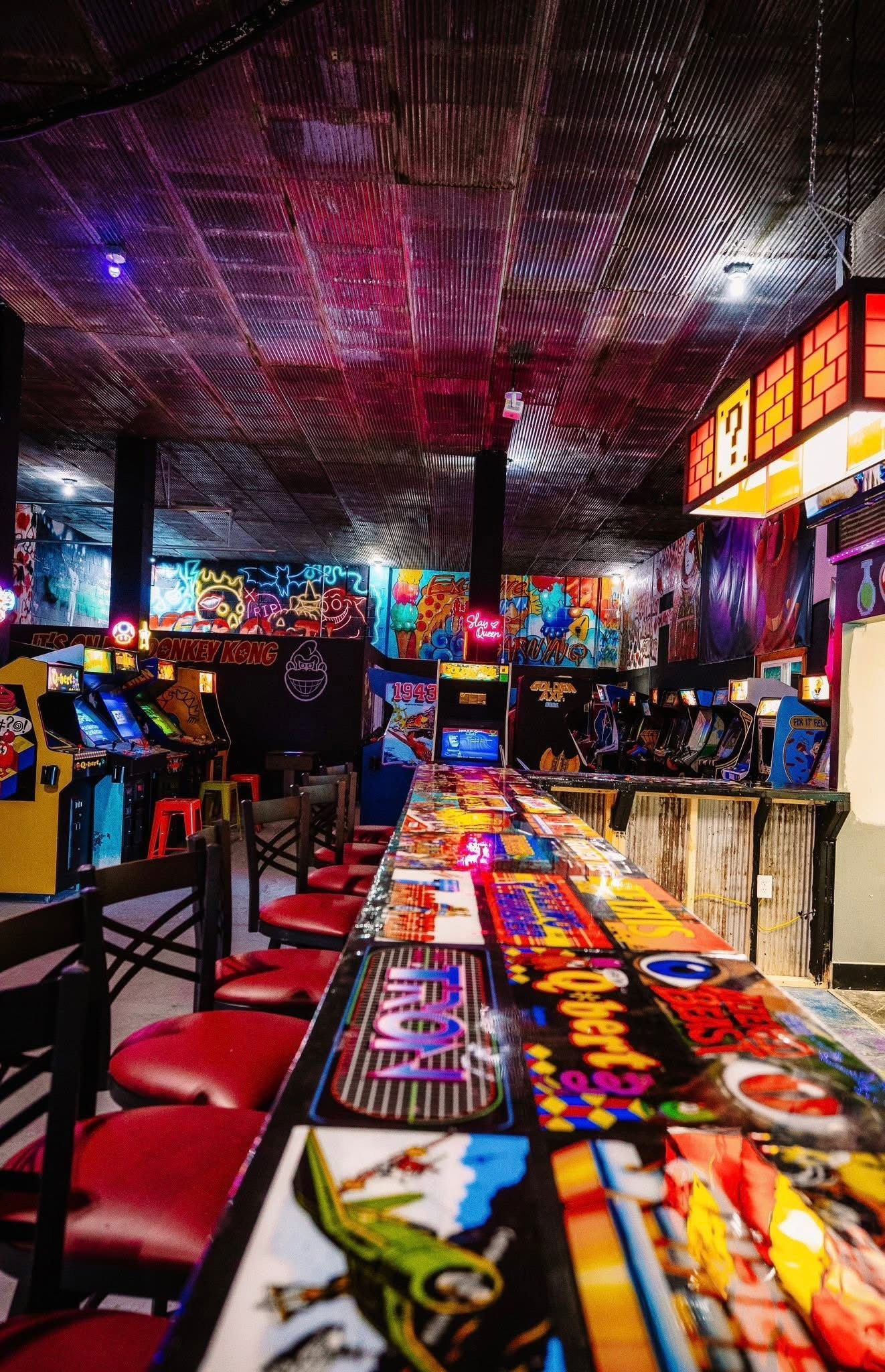 Colorful arcade with game machines and long tables under bright neon lights