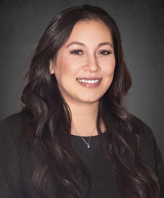 Portrait of a smiling woman with long dark hair against a dark gray background