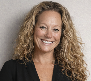 Smiling woman with curly blonde hair in a black top against a gray background