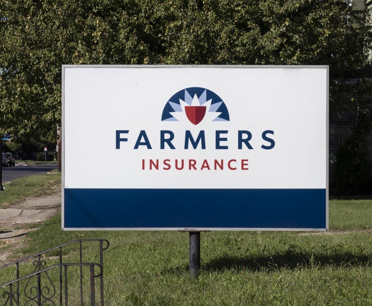 A farmers insurance sign is sitting in the grass