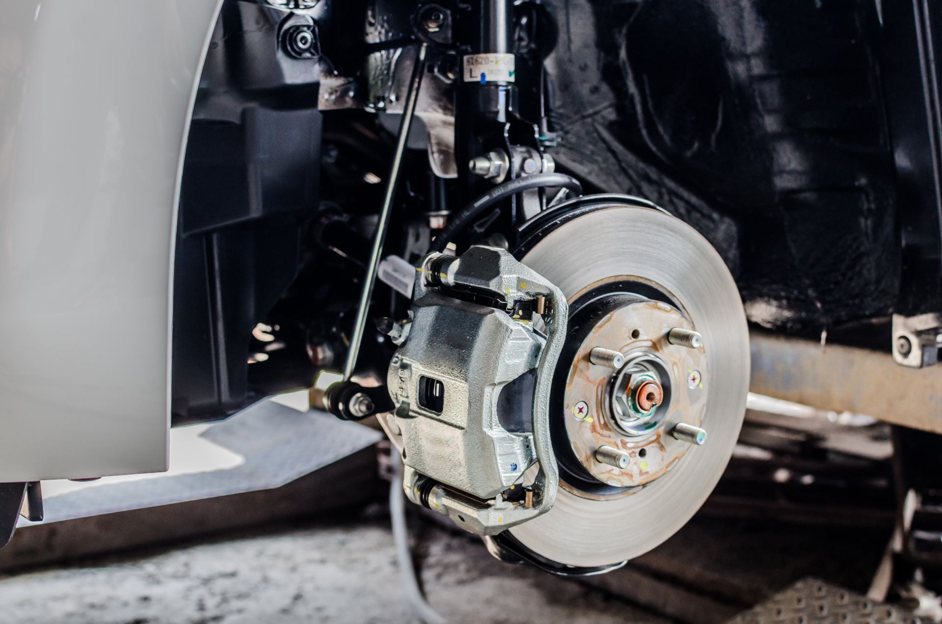 Car wheel with exposed brake rotor and caliper during repair in a garage