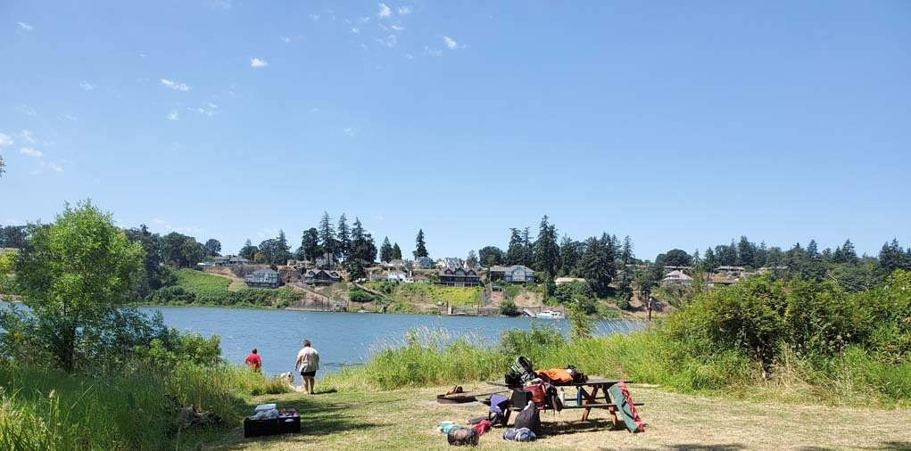 A group of people are sitting at a picnic table near a lake.