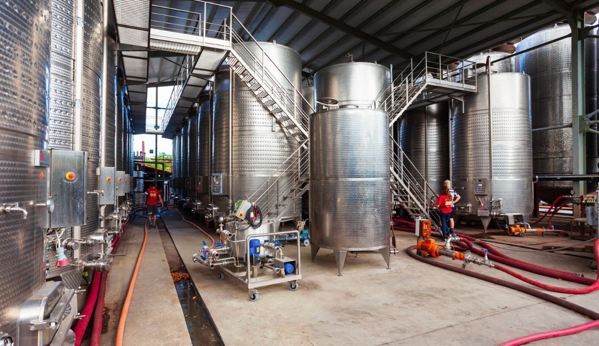 Two large white tanks are sitting next to each other in a factory.