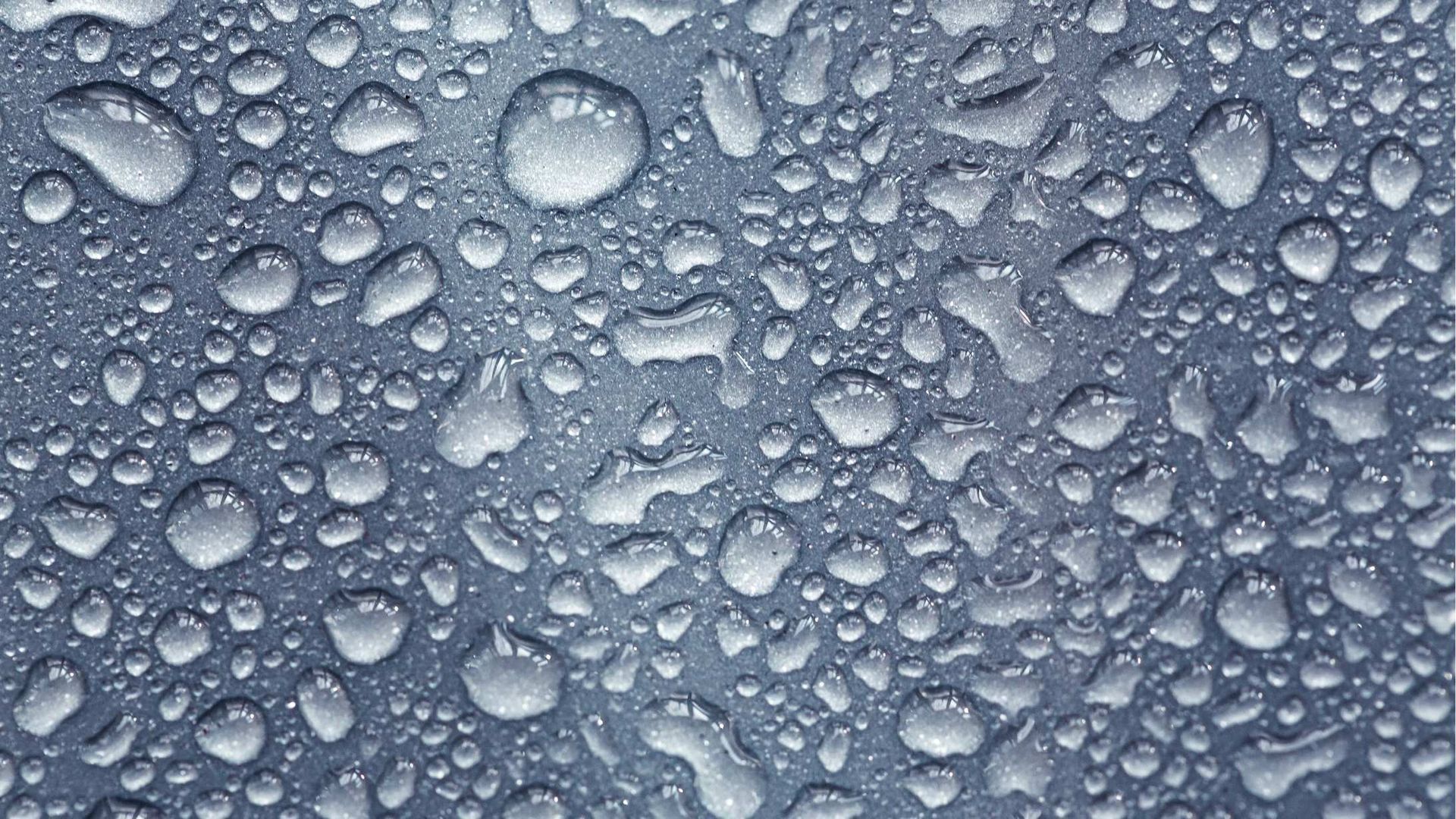 A close up of water drops on a gray surface.