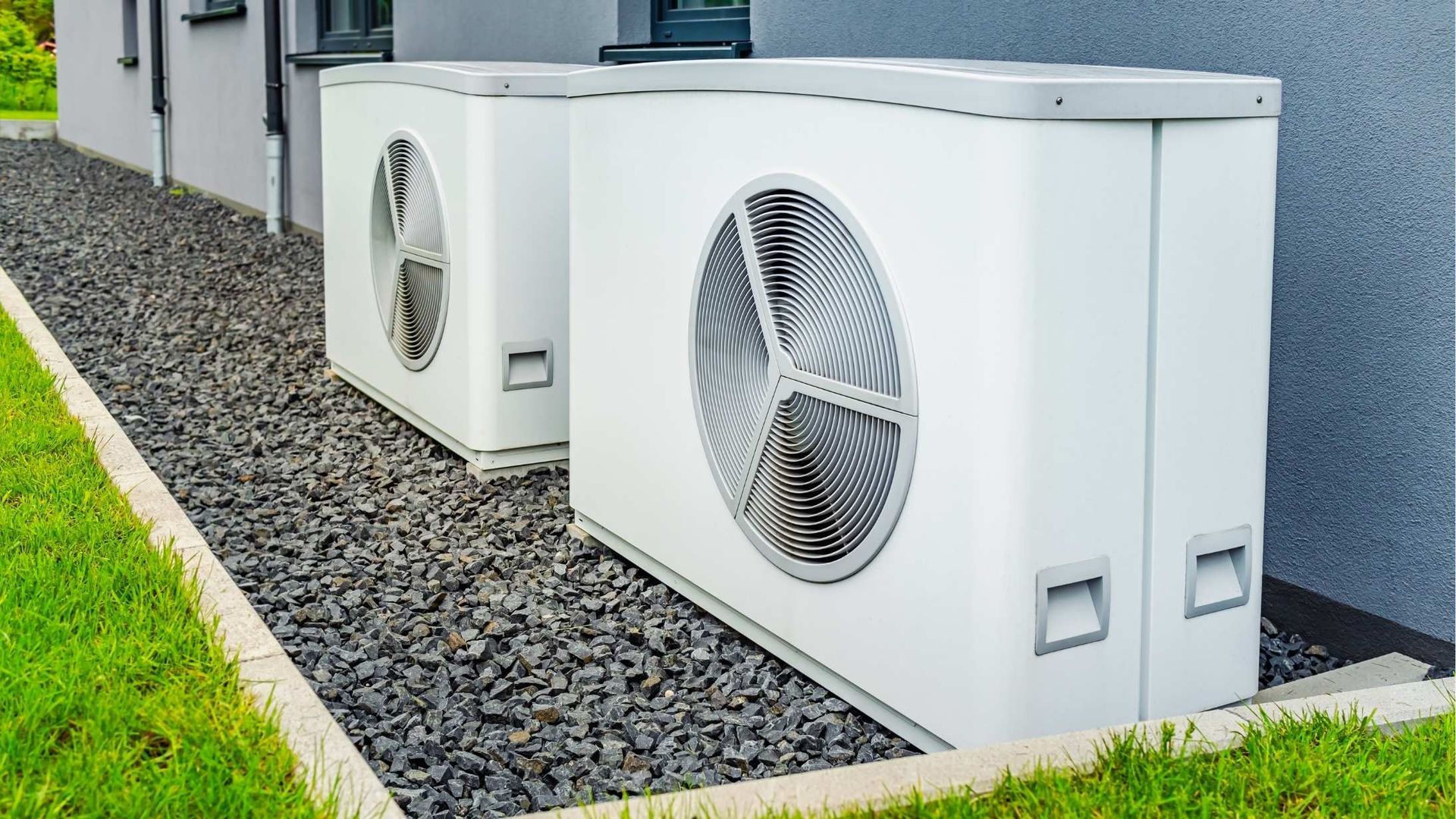 Two white air conditioners are sitting next to each other on the side of a building.