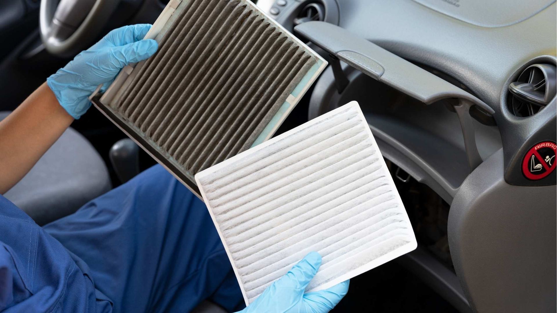 A person is holding two air filters in their hands in a car.
