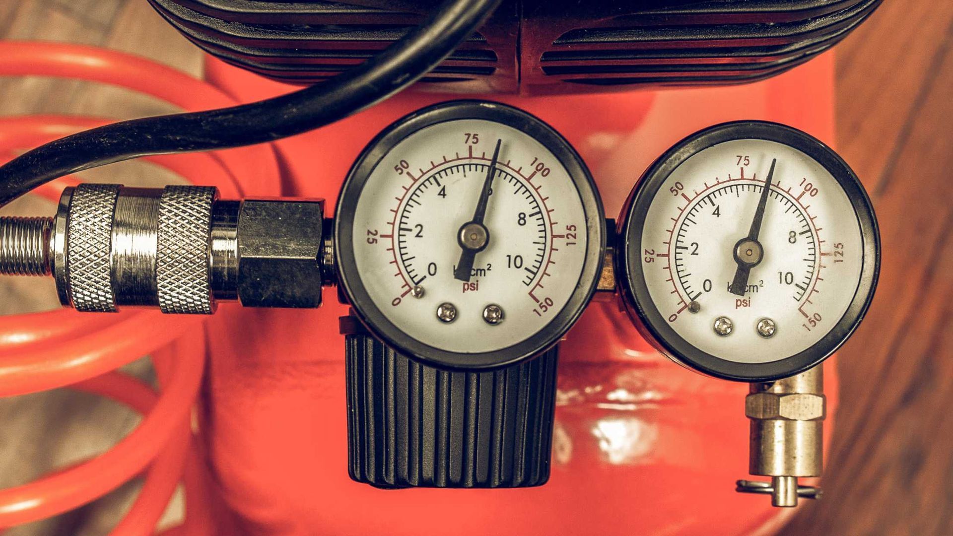 A close up of three pressure gauges on a red air compressor.