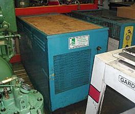 A blue machine is sitting next to a green machine in a factory.