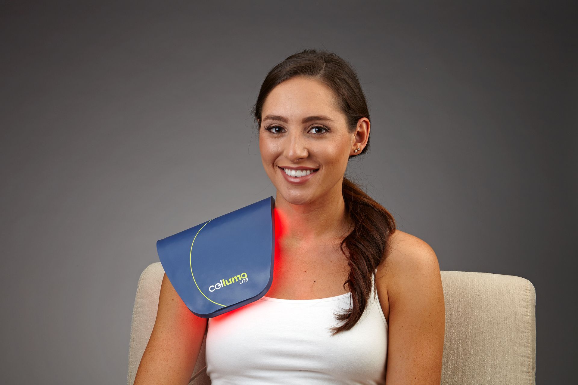 A woman is sitting in a chair with a blue pad on her shoulder