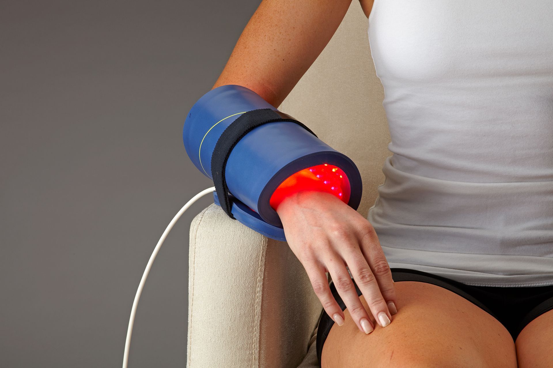 A woman is sitting in a chair with a blue device on her arm
